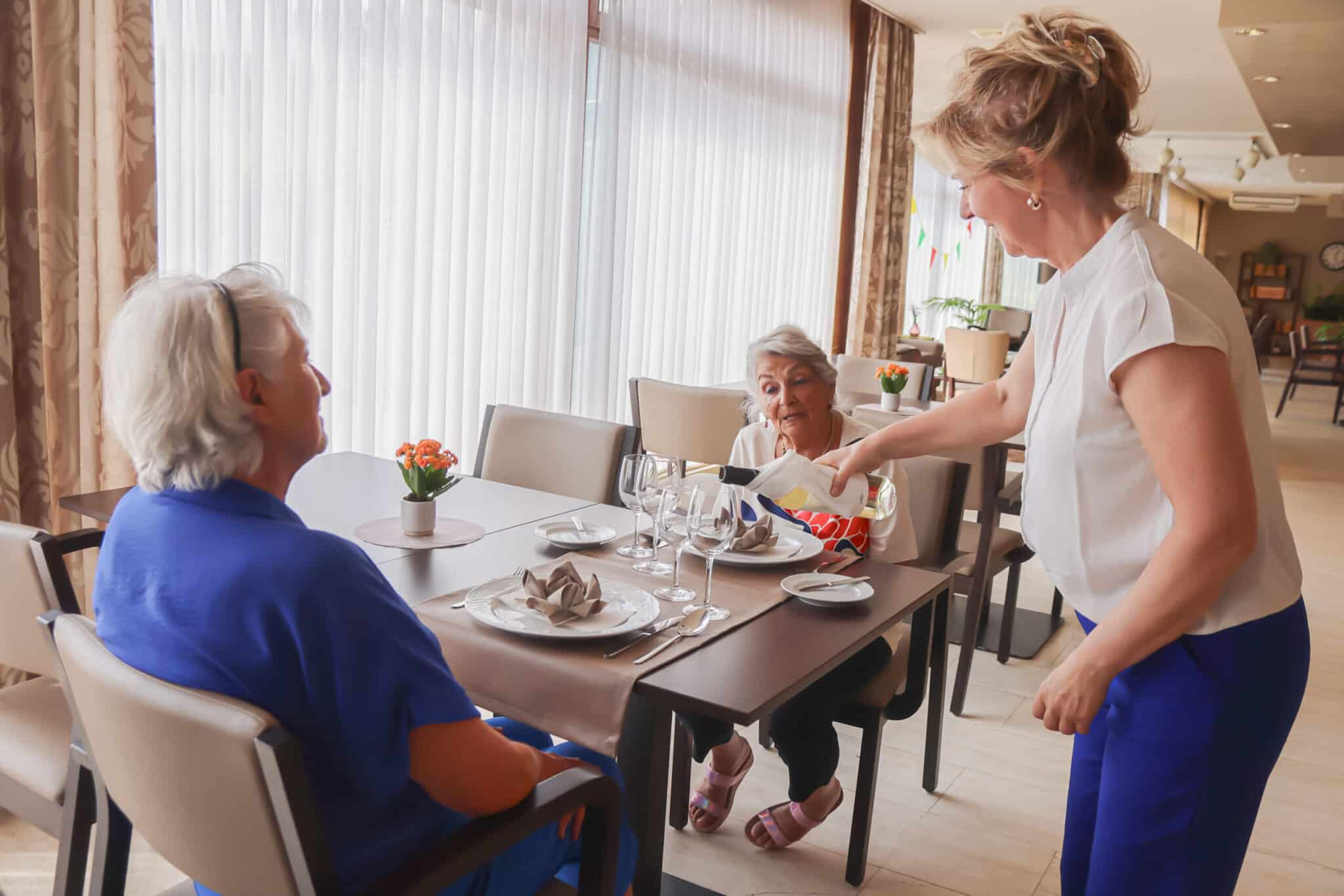 Medewerker bedient bewoners aan tafel in het sfeervolle restaurant van een service residentie hotel